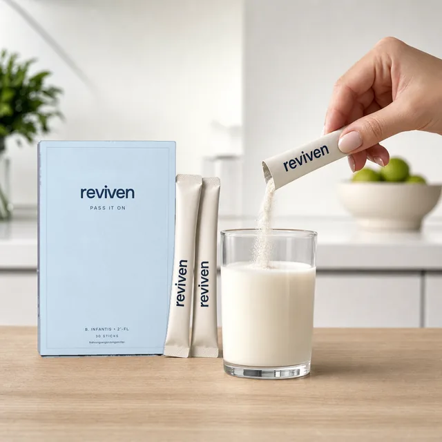 Das Pulver eines Sticks rieselt in ein Glas Milch